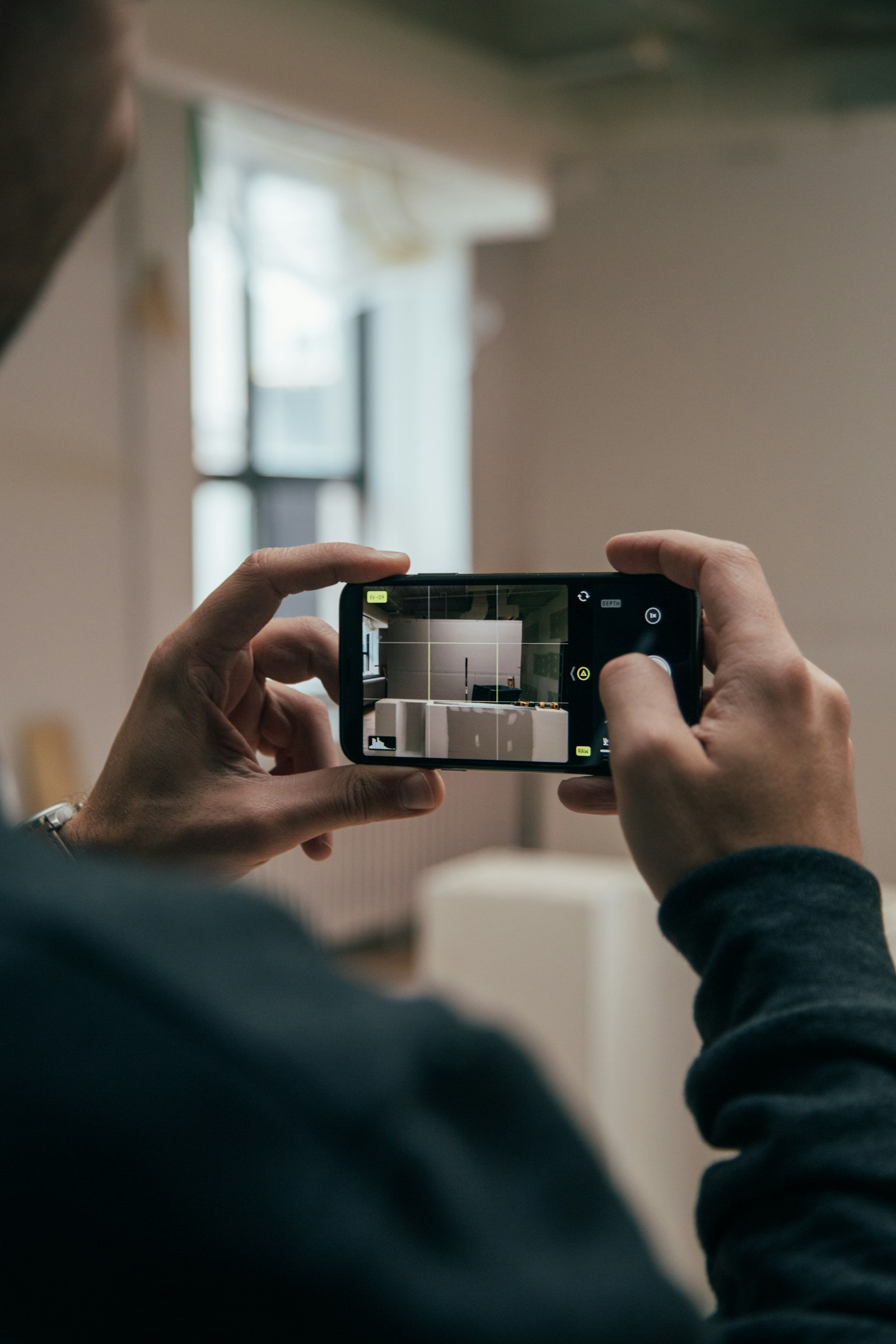 A person filming with a smartphone on a car lot