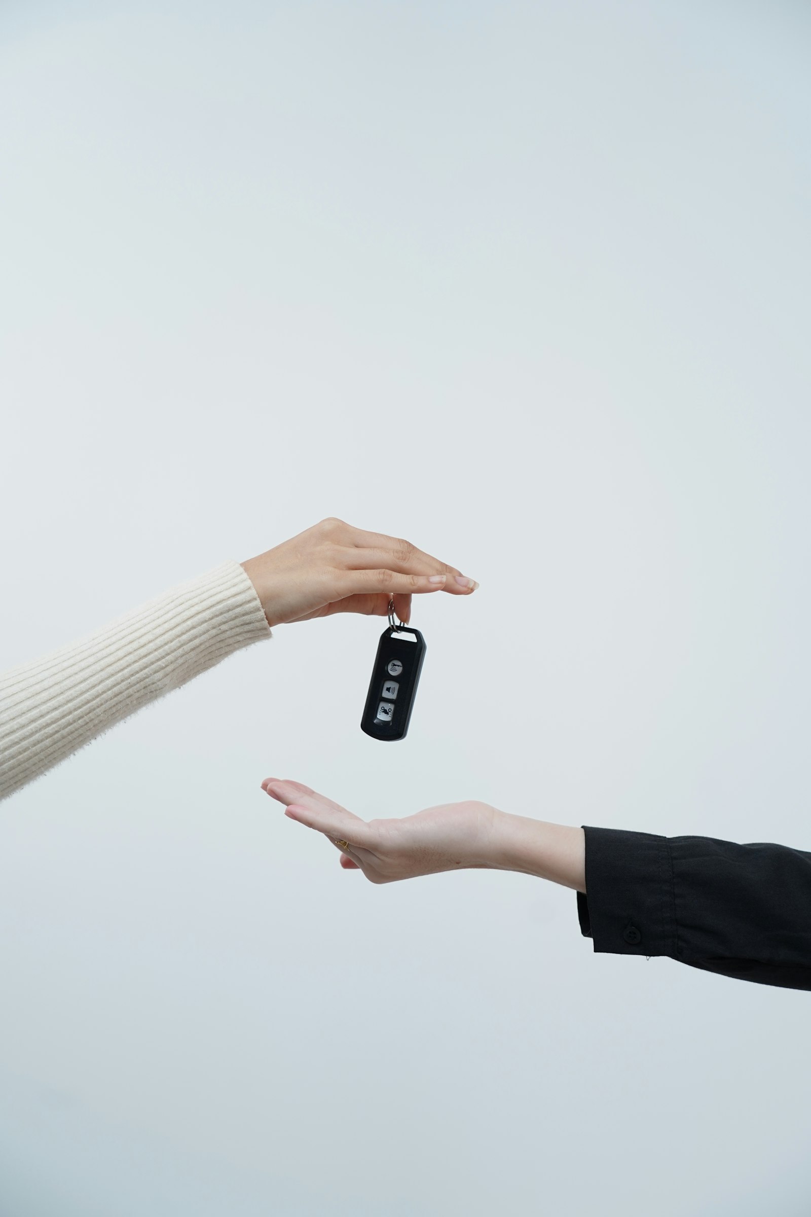 Two hands exchanging a car key fob